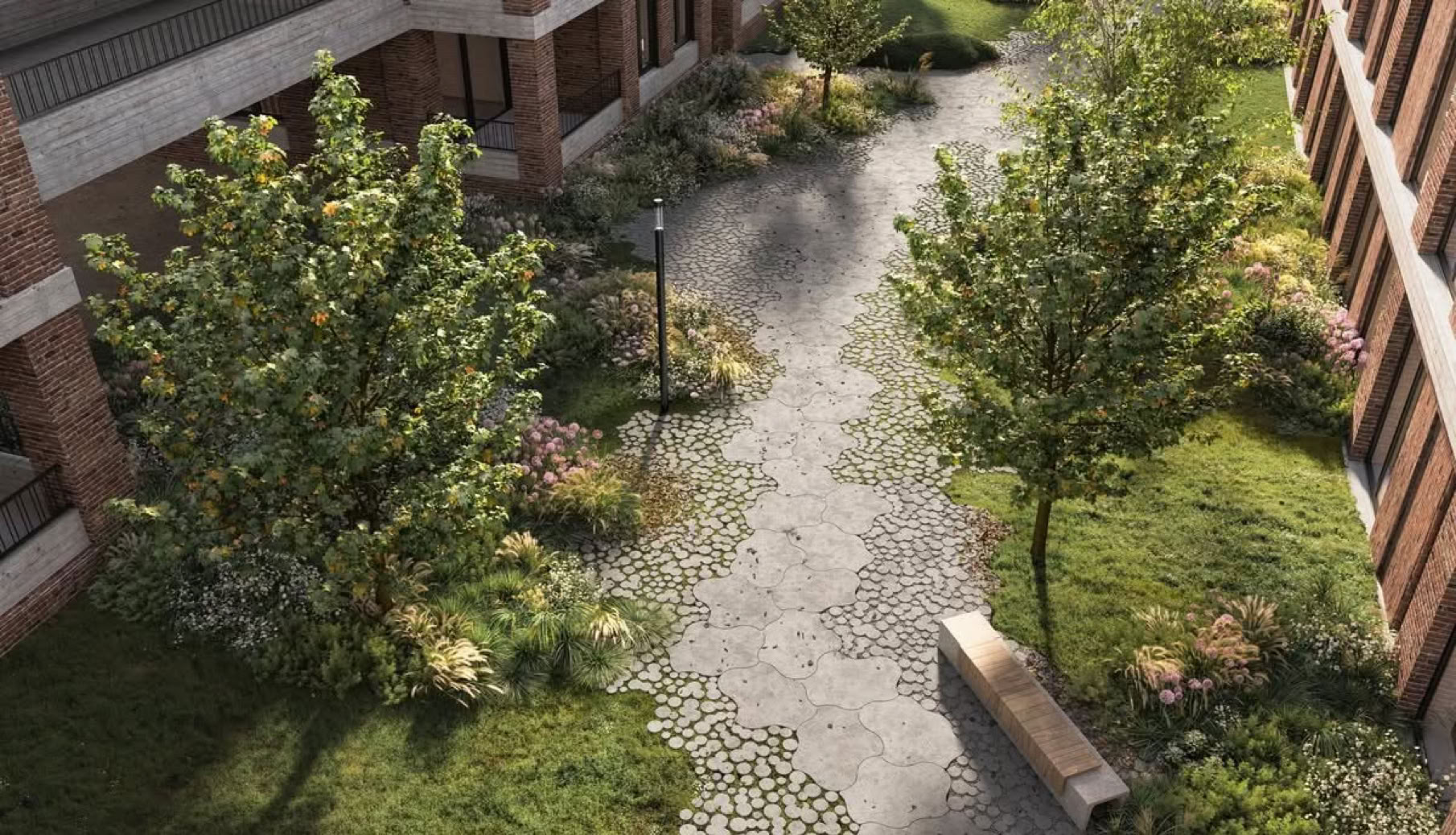 Vue aérienne d'une cour avec des arbres, un chemin pavé, un banc et des bâtiments en briques autour.